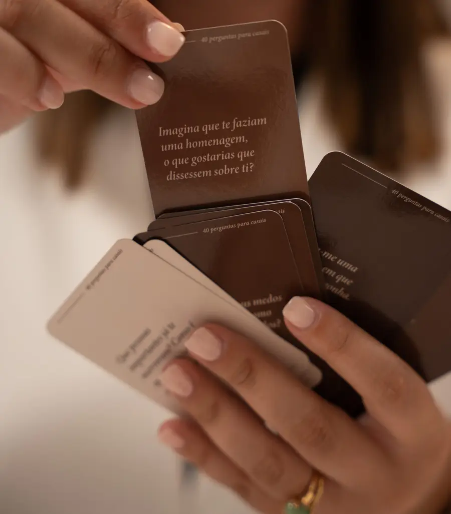 Mãos a segurar cartas do baralho 40 Perguntas para Casais
